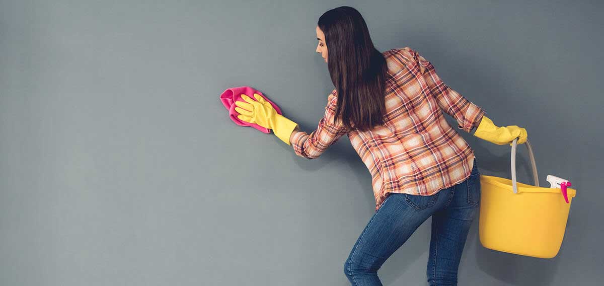 woman with bucket and gloves cleaning walls