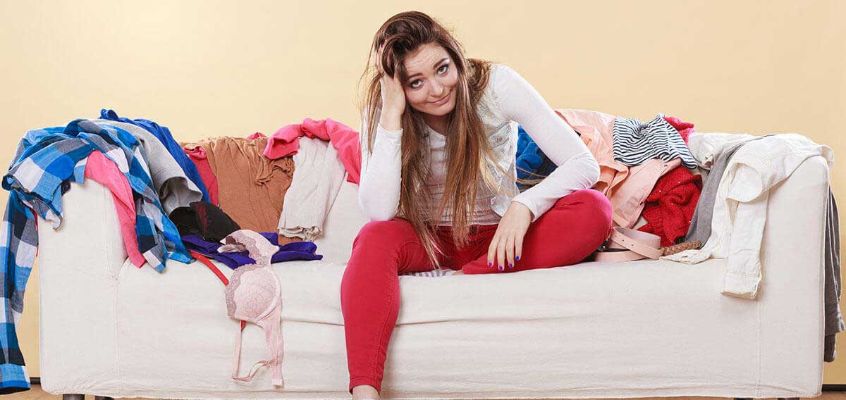 woman sitting on couch with laundry all over it