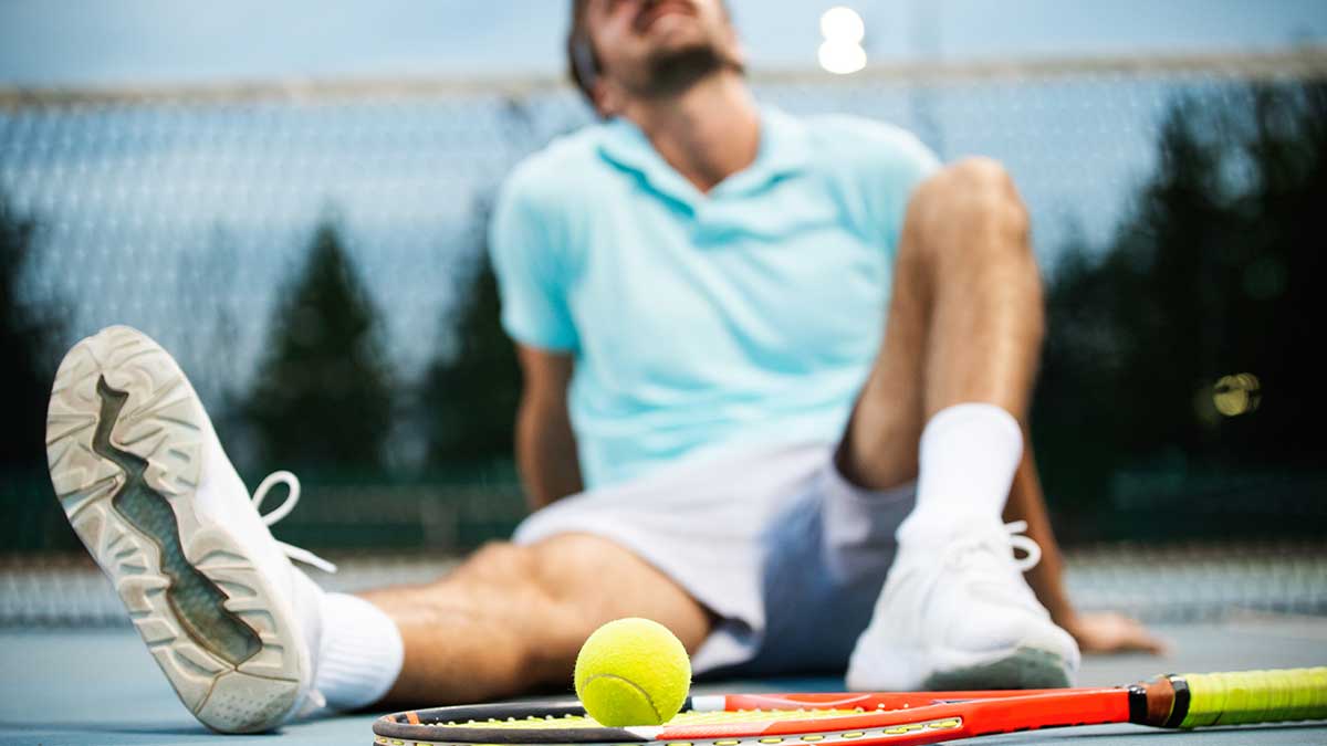 man sitting on the court in front of a tennis ball and racket