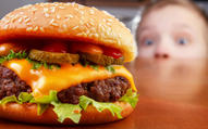 boy looking in awe at juicy cheeseburger with toppings