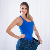woman wearing blue tank top and jeans that are too large, holding the waistband out to show size difference