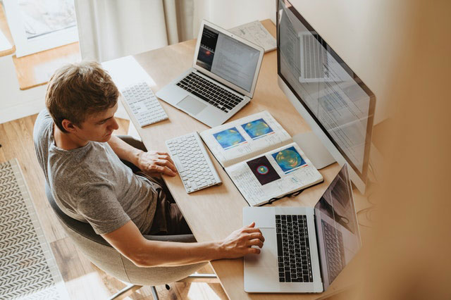 man-working-on-laptop-with-big-monitor